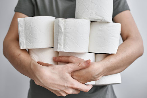 A man holding seven rolls of toilet paper.
