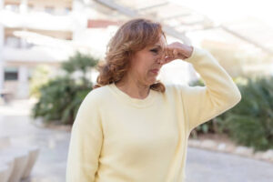 A woman holding her nose due to a bad smell outdoors.