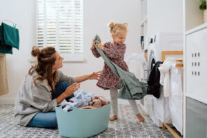 A mom and daughter doing a load of laundry.