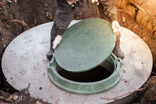 A person lifting a septic tank lid.